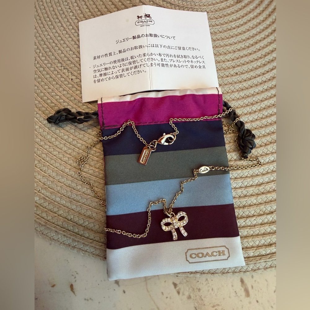 Coach Gold-Tone Crystal Bow Necklace with Legacy Striped Pouch and Coach Logo